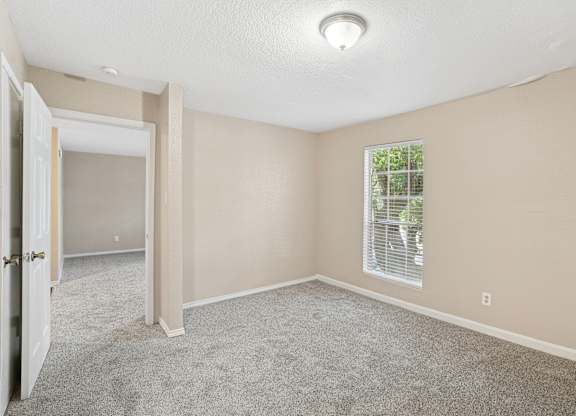 A room with a carpeted floor and a window with blinds.
