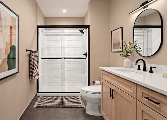 A bathroom with a toilet, sink, and a painting on the wall.