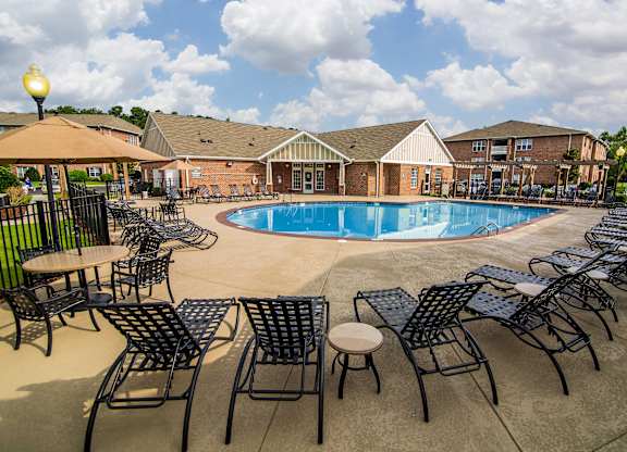 A pool surrounded by chairs and tables.