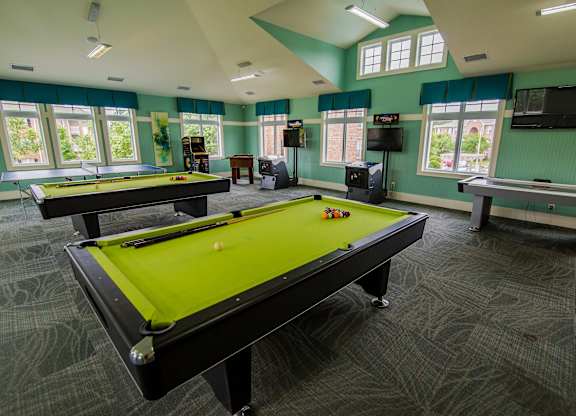 A room with a pool table and a shelf with a television on it.