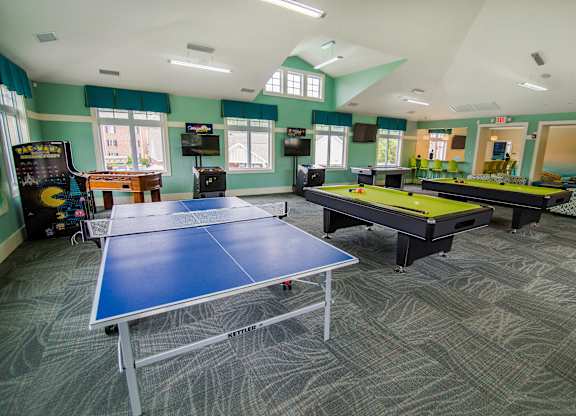A room with a ping pong table and a foosball table.