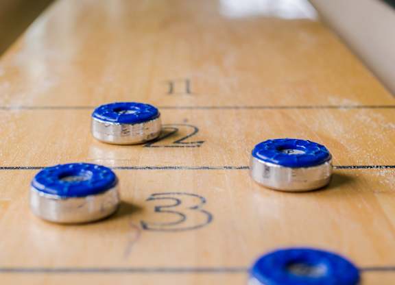 A shuffleboard table with blue and white pucks.