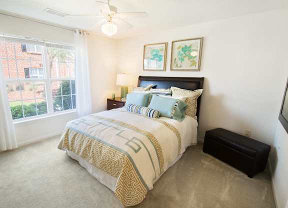 A bedroom with a bed, nightstand, and window.