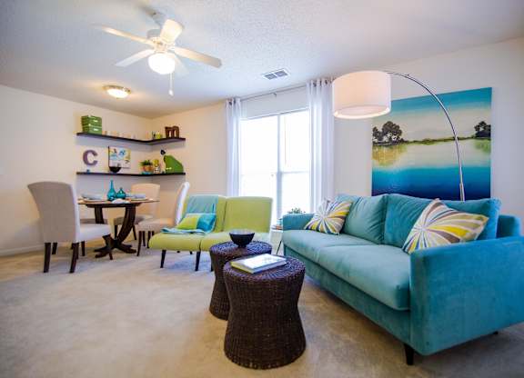 A living room with a blue couch and a painting of a beach scene on the wall.