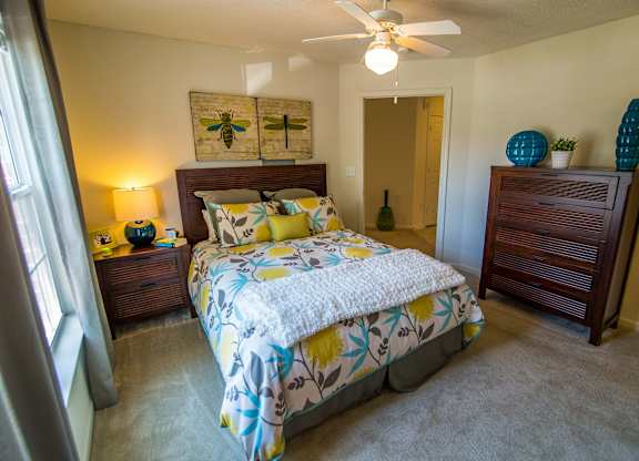 A bedroom with a bed, nightstand, and a ceiling fan.