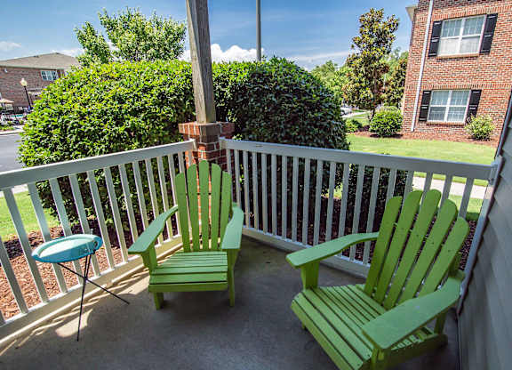 Two green chairs on a white railing.