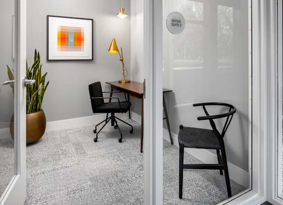 A modern office space with a chair, desk, and a framed picture on the wall.