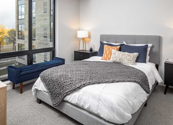 A bedroom with a large bed and a window overlooking a cityscape.
