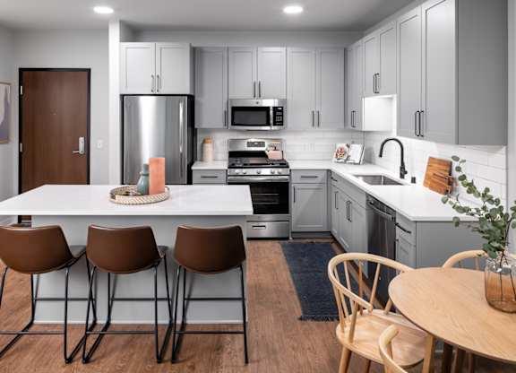 A modern kitchen with a white table and brown chairs.