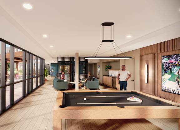 A man is standing in a room with a pool table and a television.