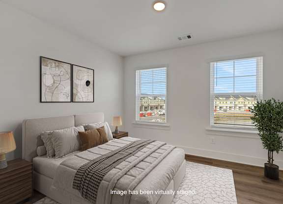 A bedroom with a large bed and a potted plant.