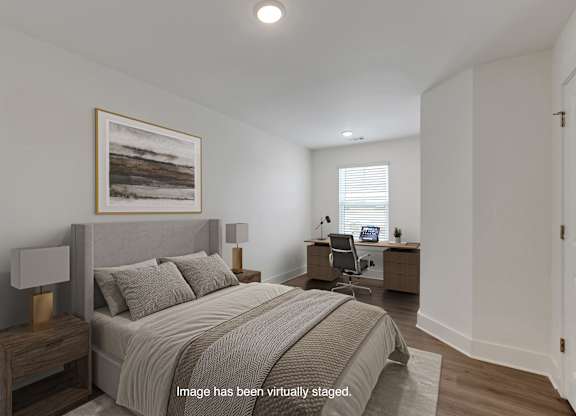 A bedroom with a bed, desk, and chair.