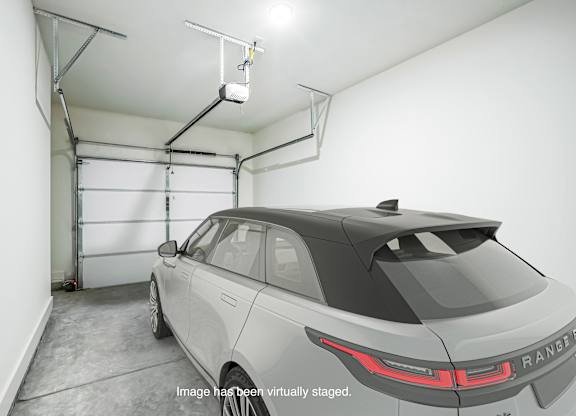 A Range Rover is parked in a garage with a lift above it.