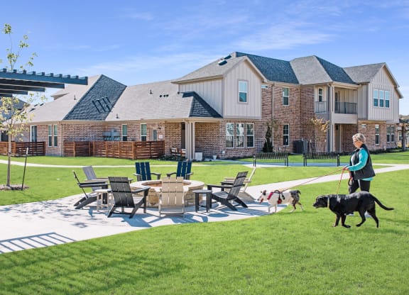a woman walking two dogs in front of an apartment complex