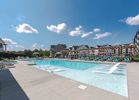 A large swimming pool surrounded by a fence and chairs.