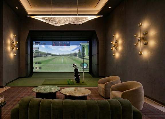 A room with a green sofa and a television screen showing a golf game.