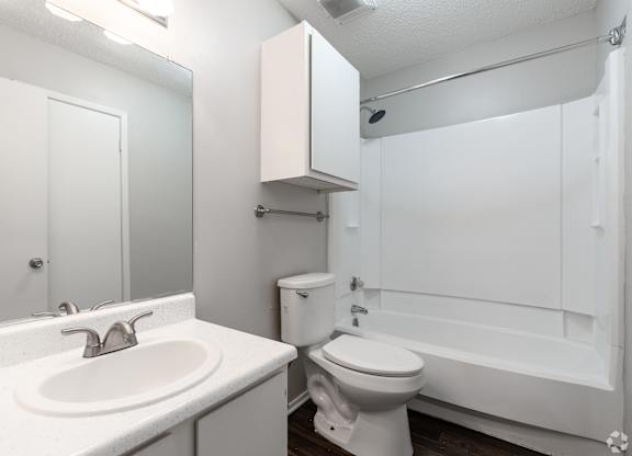 A white bathroom with a sink, toilet and bathtub.