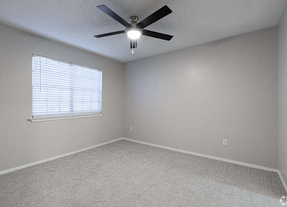 A room with a ceiling fan and a window with blinds.