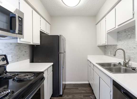 A kitchen with black appliances and white cabinets.