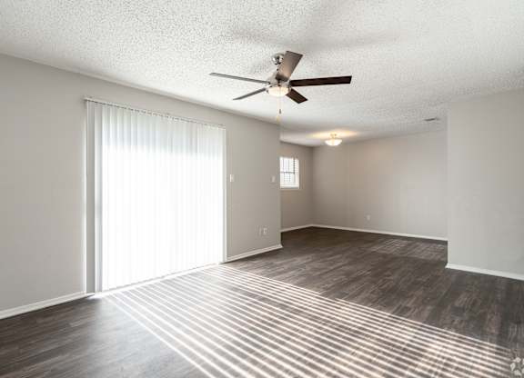 A room with a ceiling fan and sliding glass doors.