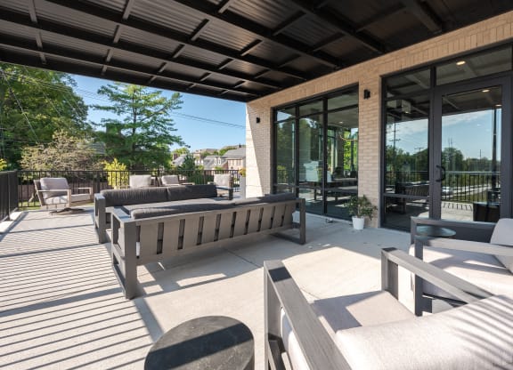 a patio with benches and chairs and glass doors