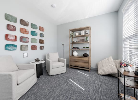 a living room with white couches and chairs and a table and a shelf with