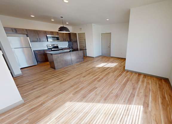 A kitchen with wooden floors and a refrigerator.