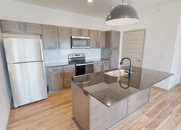 A kitchen with a refrigerator, oven, and microwave.
