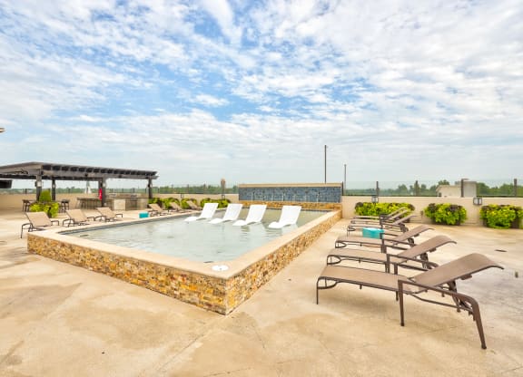 a rooftop hot tub with lounge chairs and a gazebo