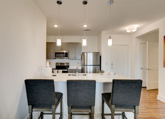 a kitchen with a large island with three chairs in front of it