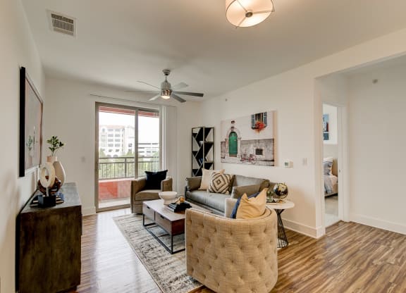 a living room with hardwood floors and a sliding glass door leading to a balcony
