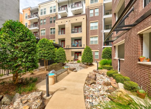 a walkway with benches in front of an apartment building