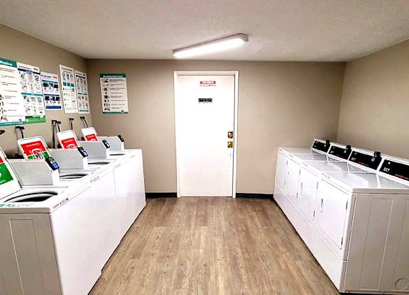 A laundromat with washers and dryers lined up on both sides of the room.