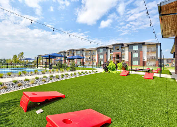 A grassy area with red benches and a pool in the background.