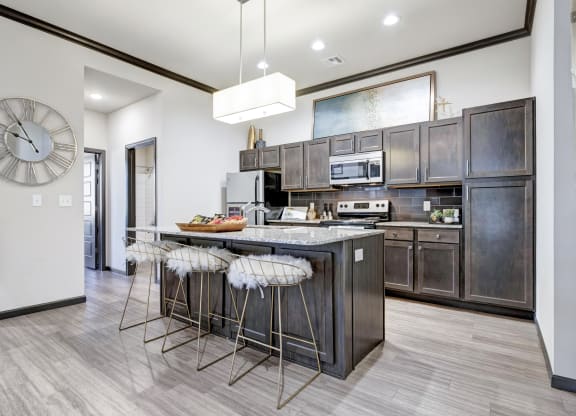 a kitchen with a large island with bar stools and a clock on the wall