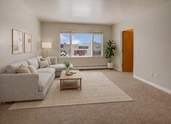 A bright living room here at Century Plaza featuring a large window that fills the space with natural light and frames a city view. A soft neutral sectional sits atop a textured rug beside a wooden coffee table, paired with modern wall art, a floor lamp, and a tall potted plant creating a calm, inviting atmosphere.