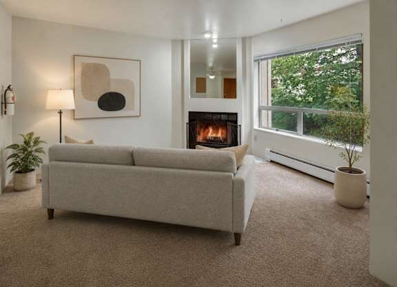 A living room with a grey couch, a fireplace, and a painting on the wall.