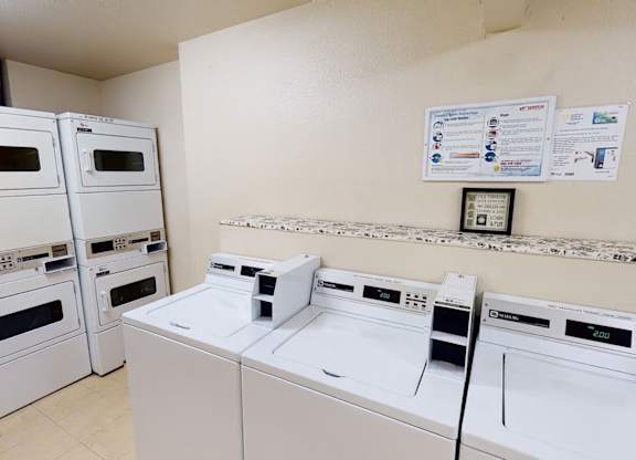 A row of white washers and four stacked dryers on the left. An open space for laundry here at Hillside Chalet.