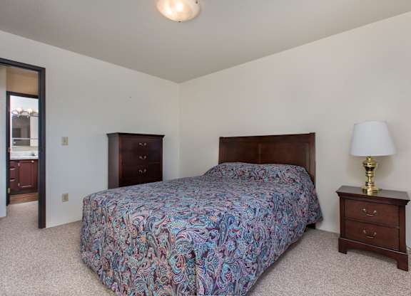 A bedroom with a bed, nightstand, and lamp.
