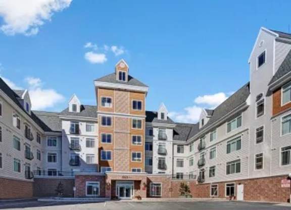 A welcoming exterior view here at Park Plaza II featuring a multi-story apartment community with classic siding, balconies, and a central entrance in a bright, well-kept setting.