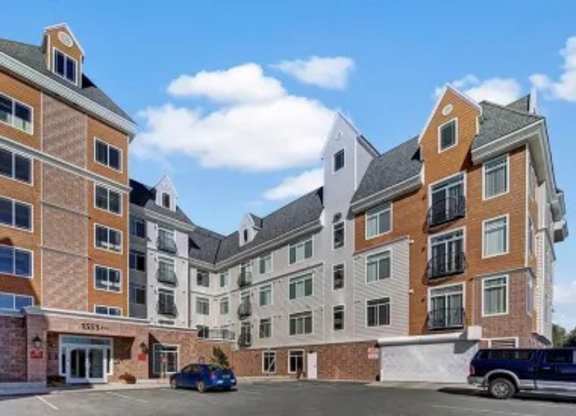 A bright exterior view here at Park Plaza II featuring a multi-story apartment community with balconies, classic siding and brick accents, and convenient on-site parking in a clean, welcoming setting.