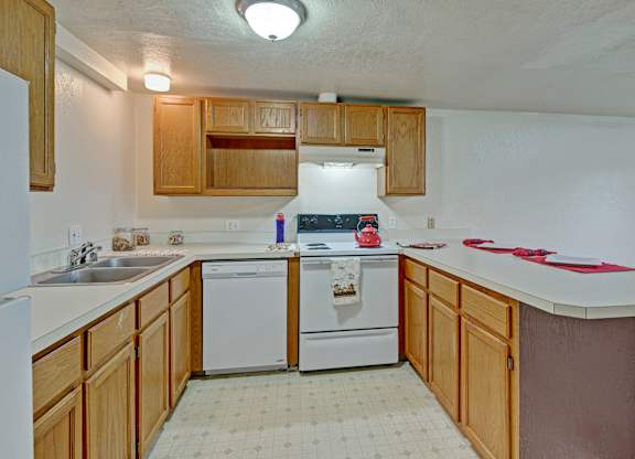 A kitchen with white appliances and wooden cabinets.