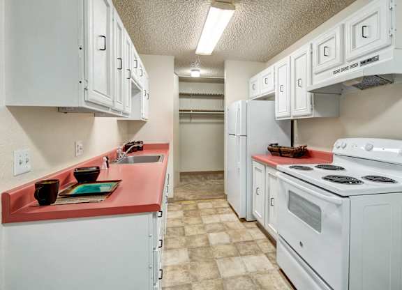 A kitchen with white cabinets and a red counter.