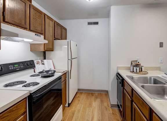 A kitchen with a stove, refrigerator, and sink.