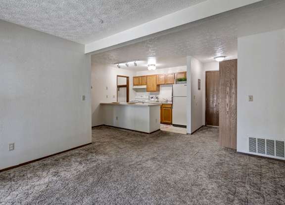 A kitchen area with white walls and a carpeted floor.