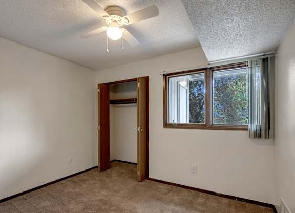 A room with a ceiling fan and a door leading to another room.