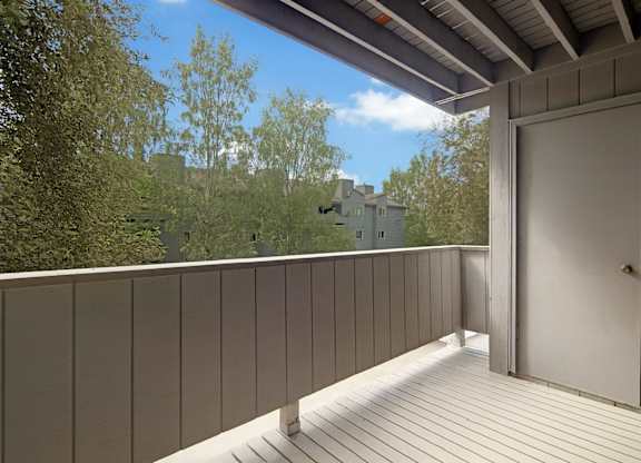 A balcony with a door and a view of a building in the distance.
