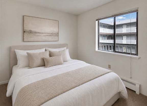 A bedroom with a large bed and a window overlooking a balcony.