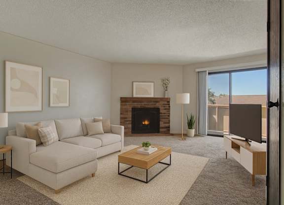 A cozy and spacious living room here at The Highlands Luxury, with a cozy fireplace, a gray sectional, small wooden coffee table, and wooden TV console with a flatscreen TV atop.