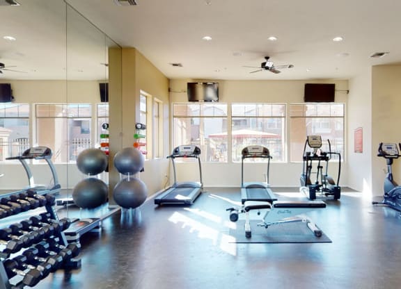 Spacious gym here at Dobson Towne Centre Apartments with treadmills, stationary bikes, free weights, and exercise balls. Sunlight pours through large windows, creating a bright, welcoming atmosphere.